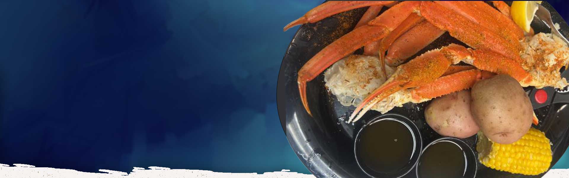 Black plate with crab legs, potatoes, corn, lemon wedge, and dipping sauces on a blue background.